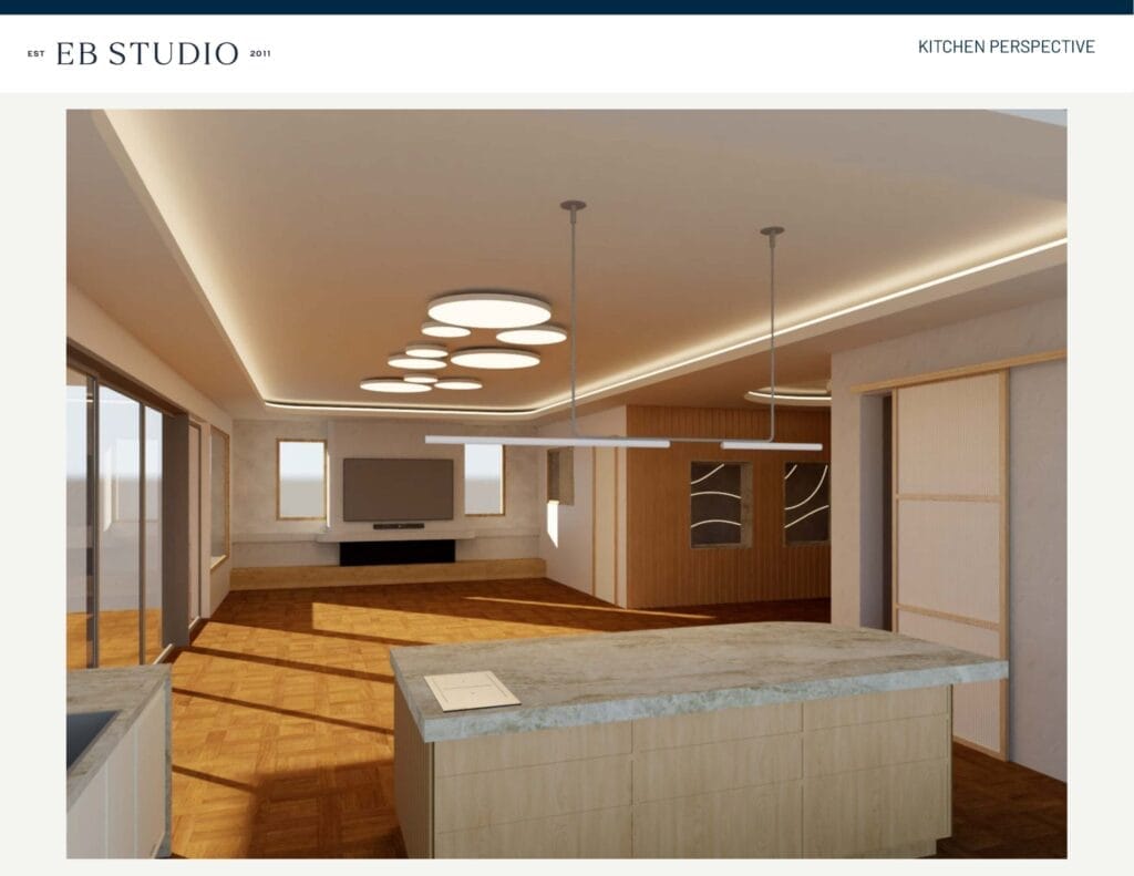 Emma Blomfield stands in a modern kitchen featuring an island, overhead pendant lights, a built-in flat screen TV, and large windows that flood the space with natural light.