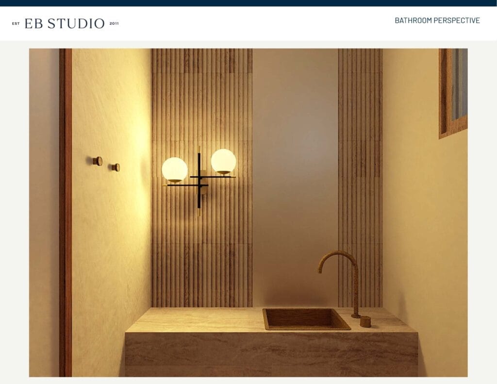 In a modern bathroom featuring a marble countertop, brass faucet, rectangular sink, light fixture with two globes, and vertically-striped wall tiles, Emma Blomfield stands elegantly.