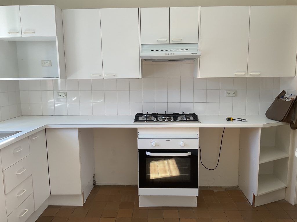 A bright kitchen with white cabinets, a gas stove, tile backsplash, and tools on the counter—ideal for renovation inspiration.